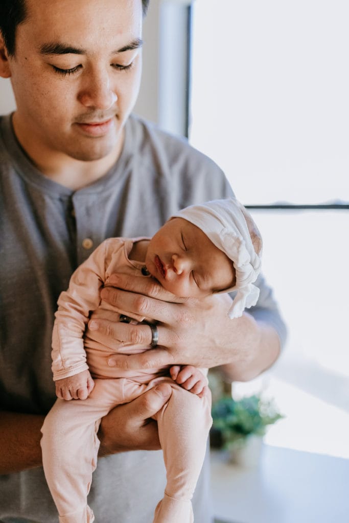 Family Photography, A young dad holds newborn baby at home